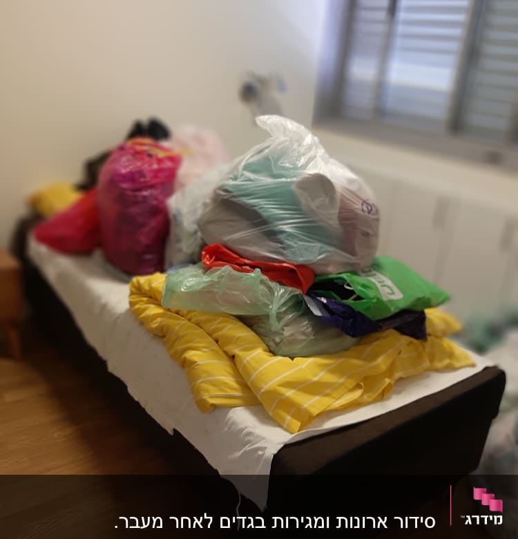מיטה עם שקיות בגדים ופריטים לארגון